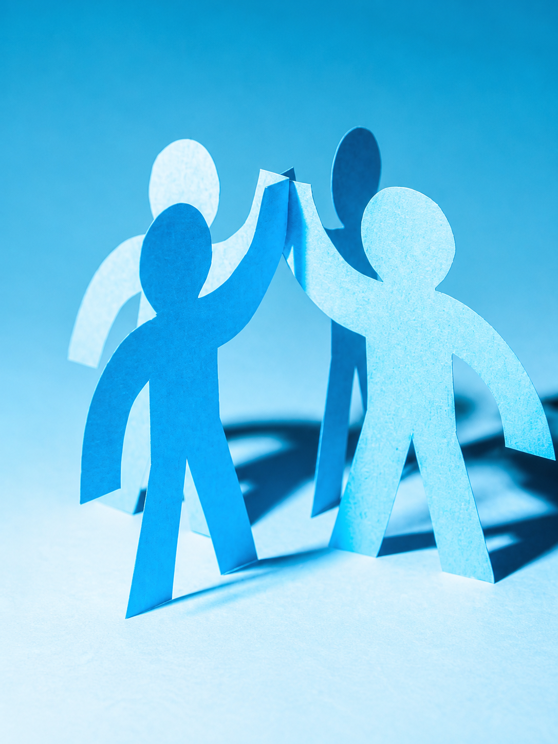 Paper figures joining hands in a gesture of partnership